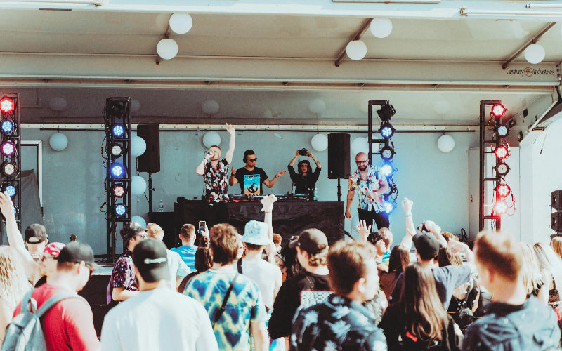 DJ set up on a stage with a crowd of people at an outdoor event.